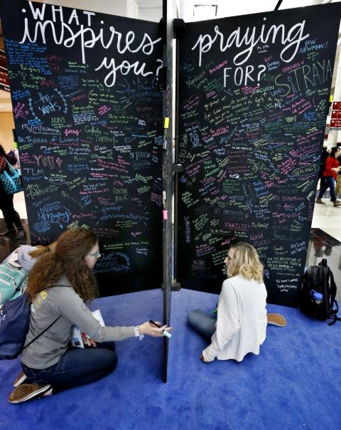 Katie Brown from the University of Toledo, Ohio, and Anna Davis from the University of Missouri Columbia, write their prayer intentions on a wall Jan. 3 during a conference sponsored by FOCUS in Chicago. (CNS/Chicago Catholic/Karen Callaway)