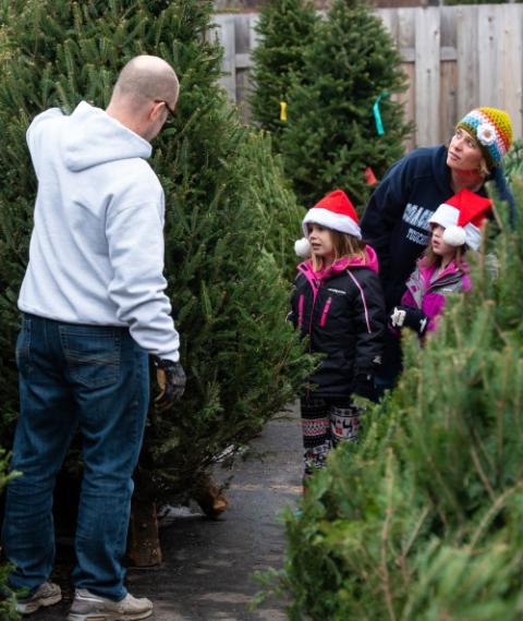 Gregg Michalski holds a Christmas tree for his wife, Joanne, and their daughters, Kendra and Paige, to examine at the Knights of Columbus Christmas tree lot in De Pere, Wisconsin, Dec. 1, 2018. (CNS/The Compass/Sam Lucero)