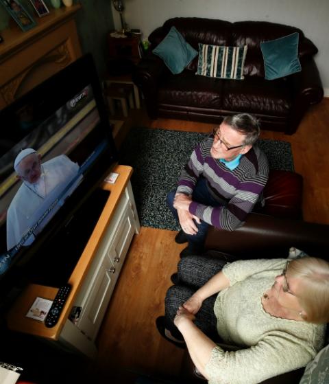 A couple watches Pope Francis from their home in Belfast, Northern Ireland, as he celebrates Easter Mass April 12 in St. Peter's Basilica at the Vatican. (CNS/Reuters/Jason Cairnduff) A couple watches Pope Francis from their home in Belfast, Northern Ireland, as he celebrates Easter Mass April 12 in St. Peter's Basilica at the Vatican. (CNS/Reuters/Jason Cairnduff)