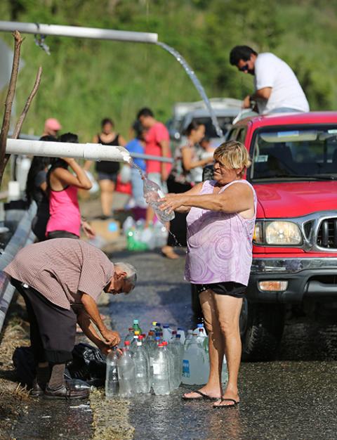 In this 2017 file photo, people fill containers with spring water from a mountain in Utuato, Puerto Rico, after Hurricane Maria devastated the island in 2017. (CNS/Bob Roller)