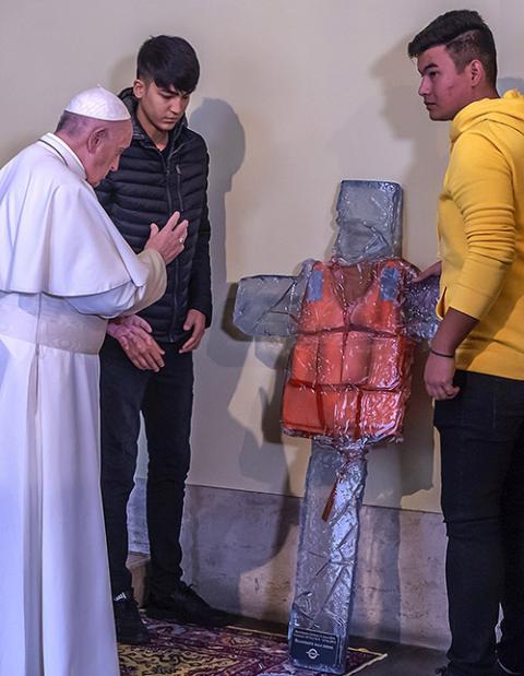 Pope Francis blesses a cross featuring a refugee's life vest during a 2019 meeting at the Vatican with refugees recently arrived in Rome from the Greek island of Lesbos. (CNS/Stefano Dal Pozzolo)