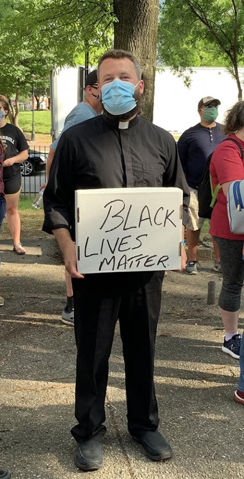 Fr. Joshua Laws, pastor of the Catholic Community of South Baltimore, holds a "Black Lives Matter" sign before the start of an interfaith prayer vigil in Baltimore June 3, 2020. (CNS/Catholic Review/Tim Swift)