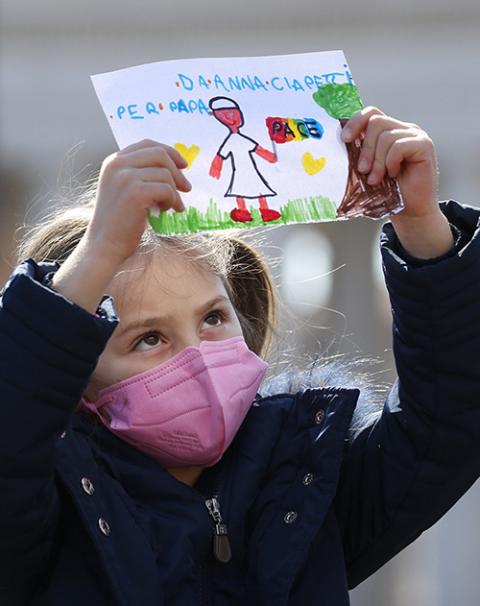 A girl holds artwork showing Pope Francis holding a peace flag as the pope leads the Angelus from the window of his studio overlooking St. Peter's Square at the Vatican March 13. (CNS/Paul Haring)