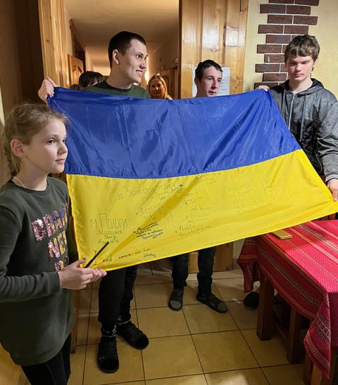 Young refugees, including Constantine on the right, present a Ukrainian flag that they had signed for David Bonior and the delegation, for coming and bearing witness, and being representatives of the U.S., at a retreat house in western Ukraine. (Courtesy of David Bonior)