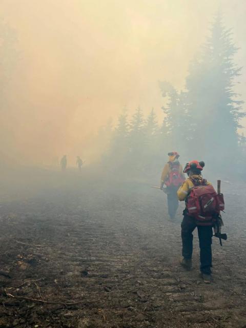 Firefighters are seen in an undated photo walking through smoke from wildfires in the Kimiwan Complex Fire SWF068 north of High Prairie, Alberta. Wildfires have always occurred, but experts say the warming climate is increasing their severity. (OSV News Alberta Wildfire handout via Reuters)