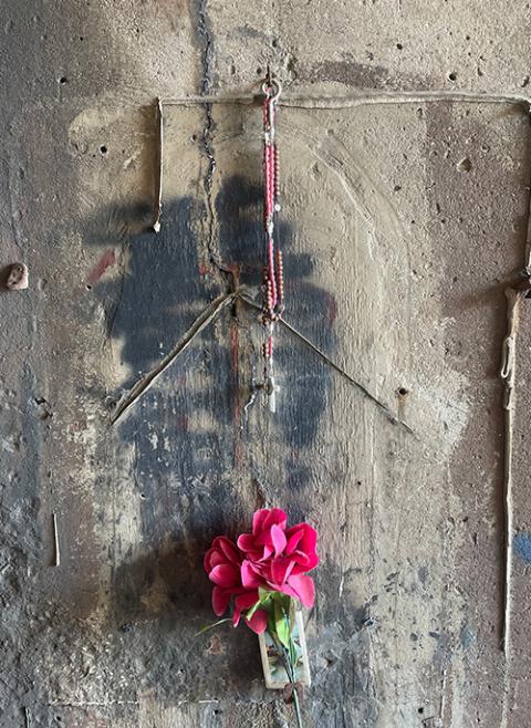 In this 2023 photo, two rosaries hang from a hook, above where the slightest outline of what some see as a head is visible, at the image known as Our Lady of the Underpass. (Gustavo Arellano)