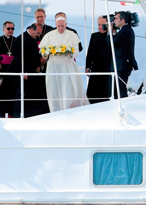 Pope Francis tosses a wreath of flowers into the Mediterranean Sea off the Italian island of Lampedusa in this July 8, 2013, file photo. The pope threw a wreath to honor the memory of immigrants who have died trying to cross from Africa to Europe. (CNS/pool)