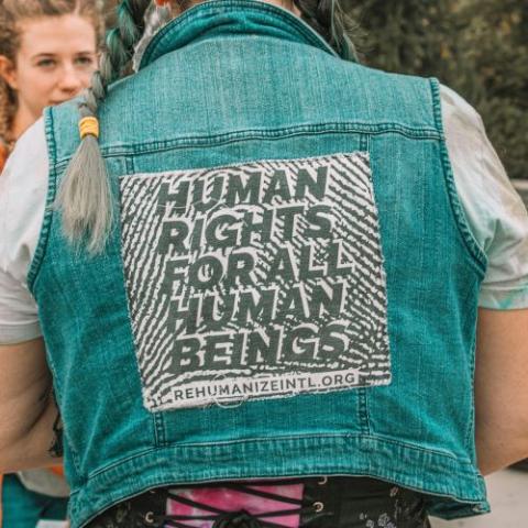 The back of a person wearing a vest that says: "Human rights for all human beings."