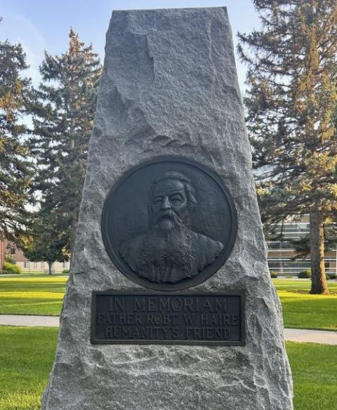 A stone monument with a big circle depicting the face of Fr. Robert Haire.