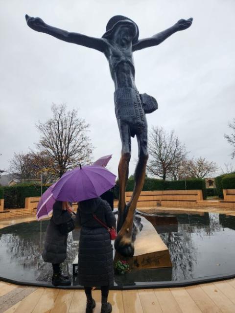 Visitors to the Marian shrine in Medjugorje, Bosnia and Herzegovina, pay homage to a statue of the crucified Christ near a contemplative area depicting the Stations of the Cross.