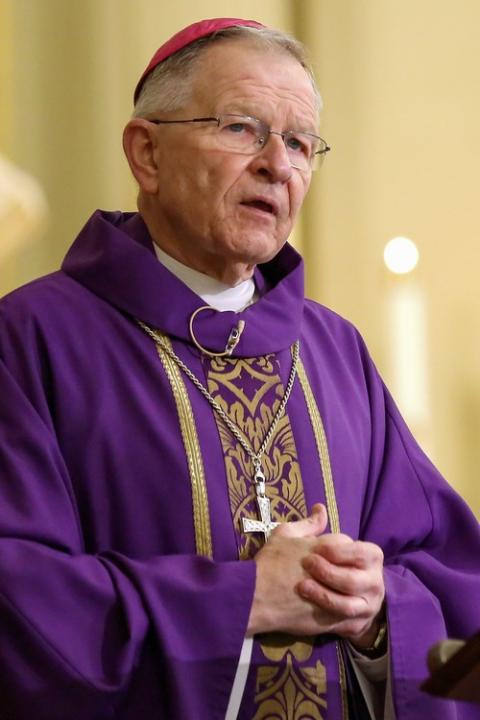Archdiocese of New Orleans, search warrant. Archbishop, vested in purple, folds hands while preaching.