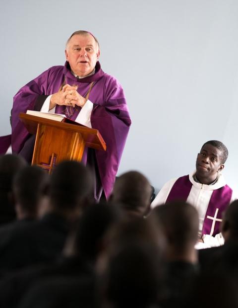 Archbishop Wenski of Miami condemns Haitian deportations Archbishop Wenksi, vested, speaks from lectern.