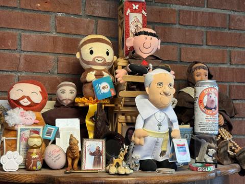 Figurine, plushies and cards depicting St. Francis and Pope Francis, assembled on a tabletop. 