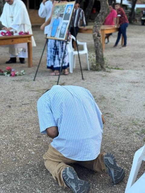 Santos Alfaro Ayala kneels April 13 in Guarjila, El Salvado, near a display of St. Oscar Romero and Blessed Fr. Rutilio Grande, to whom he prayed during his nearly three-month wrongful imprisonment. 