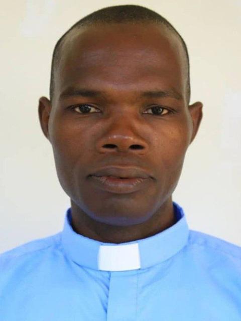 South Sudan ethnic violence against priests and other ministers. Plain headshot of Fr. Yugue wearing blue shirt and collar.