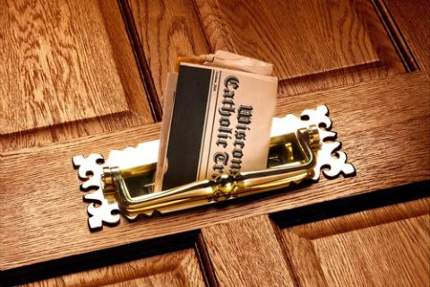Wisconsin Catholic Tribune. Newspaper peeks through front door mail slot.