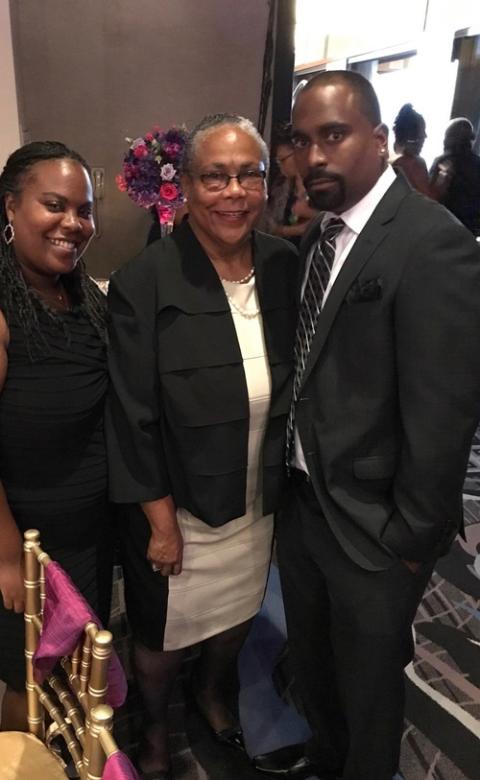 Trena Spurlock and children, survivor of Altadena fires. The three stand facing camera wearing black and white dress clothes.