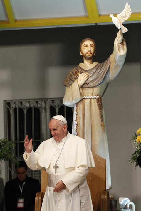 Pope Francis waves near a statue of St. Francis of Assisi as he meets with patients at a hospital in Rio de Janeiro July 24, 2013. (CNS/Paul Haring)