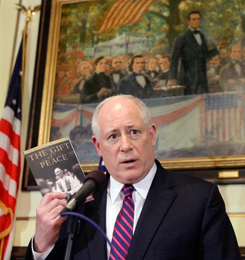 Holding a book by the late Cardinal Joseph Bernardin of Chicago, Illinois Gov. Pat Quinn speaks with reporters in his office after signing legislation abolishing the state's death penalty, at the Illinois State Capitol in Springfield, March 9, 2011. (AP/Seth Perlman)