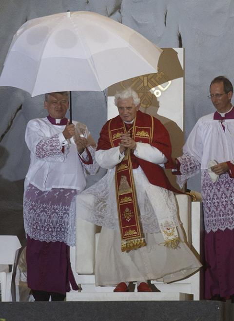 An aide holds an umbrella for Pope Benedict XVI as rain and wind moves through the Cuatro Vientos airfield in Madrid during the World Youth Day vigil Aug. 20, 2011. The pope and more than 1 million young people continued with the prayer service despite the storm. (CNS/Paul Haring)