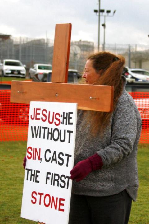 A protester holds a cross and sign during an anti-death penalty protest outside the South Dakota State Penitentiary in Sioux Falls Nov. 4, 2019, where Charles Russell Rhines was executed by lethal injection for the death of a former co-worker. (AP/Stephen Groves)