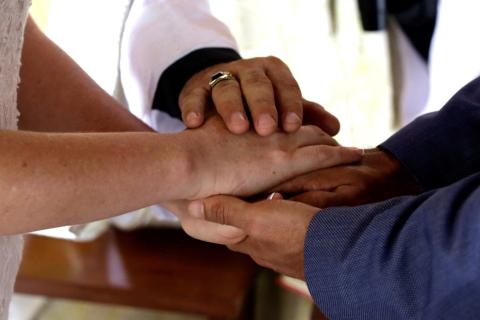 A priest's hand over the clasped hands of a wedded couple