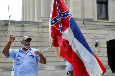 June 30, an employee at the Mississippi Capitol raises and lowers the former state flag, adopted in 1894 with the Confederate emblem. June 30, Mississippi Gov. Tate Reeves signed a bill into law to replace it. A commission reviewed about 3,000 design prop
