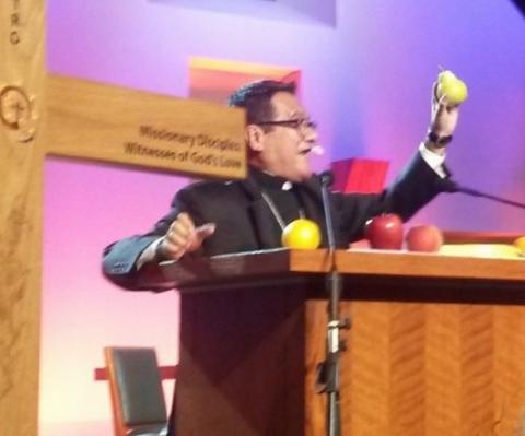 Detroit Auxiliary Bishop Arturo Cepeda holds up a pear he was given during a keynote address Sept. 22 at the V Encuentro in Grapevine, Texas. (NCR photo/Maria Benevento)