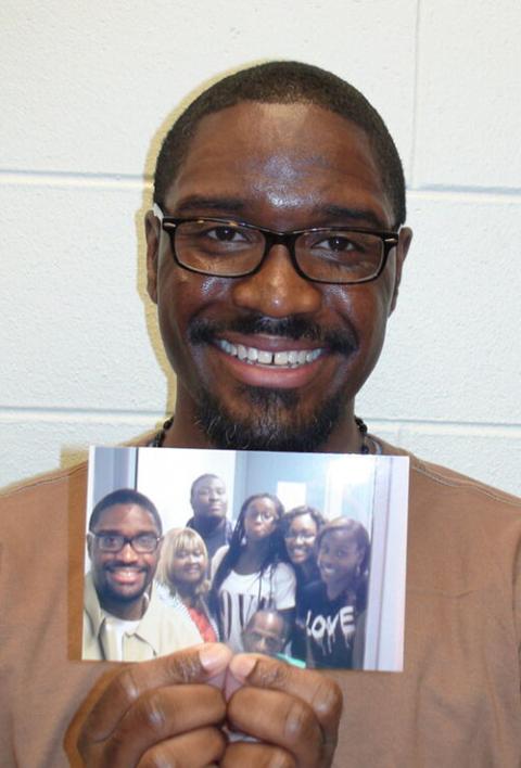 Brandon Bernard shows a photo of a prison visit with his family. (Brandon Bernard’s Defense Team)