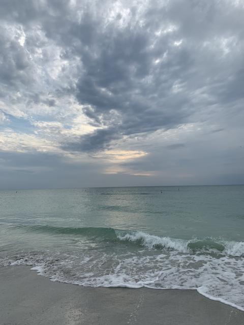 waves rolling into a beach with gathering clouds overhead waves rolling into a beach with gathering clouds overhead