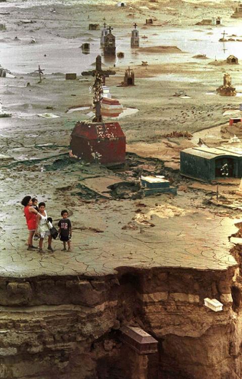 A family looks over a cemetery damaged by mudslides and flooding from El Niño rains in Trujillo, Peru, Feb. 12, 1998. (CNS/Reuters) A family looks over a cemetery damaged by mudslides and flooding from El Niño rains in Trujillo, Peru, Feb. 12, 1998. (CNS/Reuters)