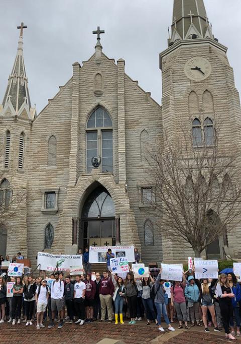 Hundreds of Creighton University students demonstrate outside St. John's Church on the Omaha, Nebraska, campus in April 2019, pressing the Jesuit school to take increased action on climate change, including divesting its endowment from fossil fuels.