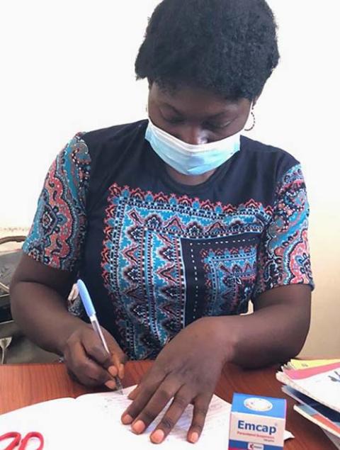 Grace Maikani, a nurse at Area 1 IDP Camp in Abuja, Nigeria, takes notes while on duty. (Chinedu Asadu)