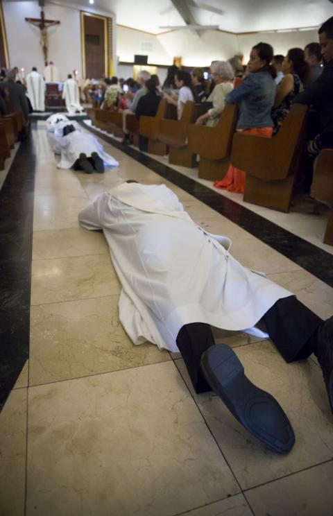 Ordinands lie prostrate as the community prays for the blessing of the Holy Spirit to descend upon them at their ordination. (Jon Rou)