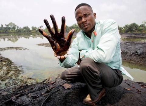 A man holds up an oil-covered hand in the Niger Delta area, May 30. 2019. (Wikimedia Commons/Ucheke)