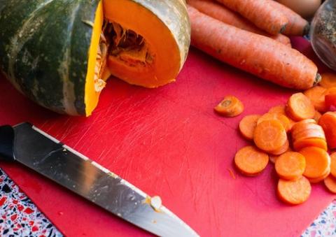 Meal preparation evokes sharing. Image of a cutting board with squash and carrots (Unsplash/Louis Hansel)