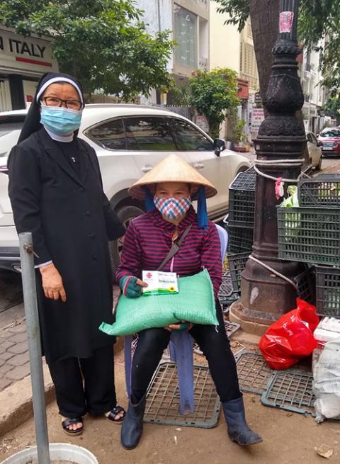 Lovers of the Holy Cross Sr. Mary Nguyen Thi Hau hands gifts to a woman who works as a scrap collector in Ho Chi Minh City, Vietnam. (Courtesy of Mary Nguyen Thi Hau)