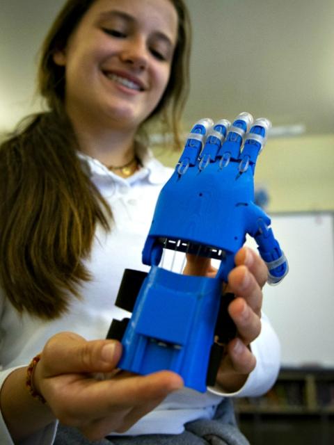 Rosali Patterson tests out the prosthetic hand she helped design and produce for underprivileged children using St. John Fisher School's 3-D printer technology. (CNS/Chaz Muth)