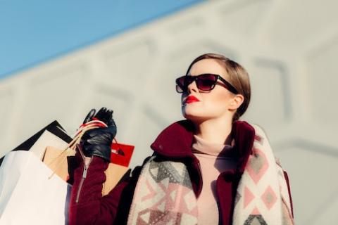 A woman in sunglasses holds several shopping bags (Unsplash/Freestock)