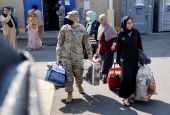 U.S. Army soldiers at the Dulles Expo Center in Chantilly, Va., assist Afghanistan families as they depart an evacuees' processing center Aug. 25. (CNS/Reuters/Jonathan Ernst)