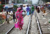 A woman carries drinking water along railroad tracks Sept. 15 in a poor section of Dhaka, Bangladesh. (CNS/Mohammad Ponir Hossain, Reuters)