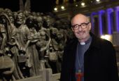 Canadian Cardinal Michael Czerny, undersecretary for migrants and refugees at the Vatican Dicastery for Promoting Integral Human Development, poses for a photo at the "Angels Unawares" statue in St. Peter's Square at the Vatican Dec. 15, 2020. In a virtua