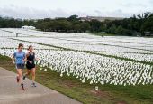 Women in Washington run past an exhibition of white flags at the National Mall Sept. 17, that represent Americans who have died of the coronavirus disease. (CNS/Reuters/Joshua Roberts)