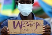 A civilian holds a placard in support of peace as he celebrates the signing of peace agreement between Sudan's transitional government and Sudanese revolutionary movements to end decades-old conflict, in Juba, South Sudan, in this Oct. 3, 2020, file photo