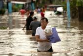 A man carries his belongings through floodwaters Sept. 26, 2022, after Typhoon Noru hit Bulakan, Philippines. Noru left a trail of destruction in northern Philippine provinces and was headed toward Vietnam. (CNS photo/Eloisa Lopez, Reuters)