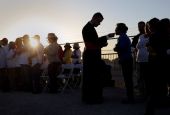Migrants watching Pope Francis' Mass in Juarez, Mexico, from a levee along the banks of the Rio Grande in El Paso, Texas, take part in Communion, Feb. 17, 2016. 
