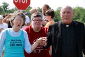 Oblate Fr. Carl Kabat, right, holds the hand of organizer Jane Stoever, left, as they lead protesters across the property line at the National Nuclear Security Administration's Kansas City Plant July 13, 2013, in Kansas City, Missouri. 