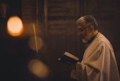 Picture of a priest holding a book (Unsplash/Tamara Govedarov)