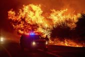 Flames lick above vehicles on Highway 162 as the Bear Fire burns in Oroville, California, on Sept. 9, 2020. The blaze, part of the lightning-sparked North Complex, expanded rapidly as winds buffeted the region. (AP Photo/Noah Berger)