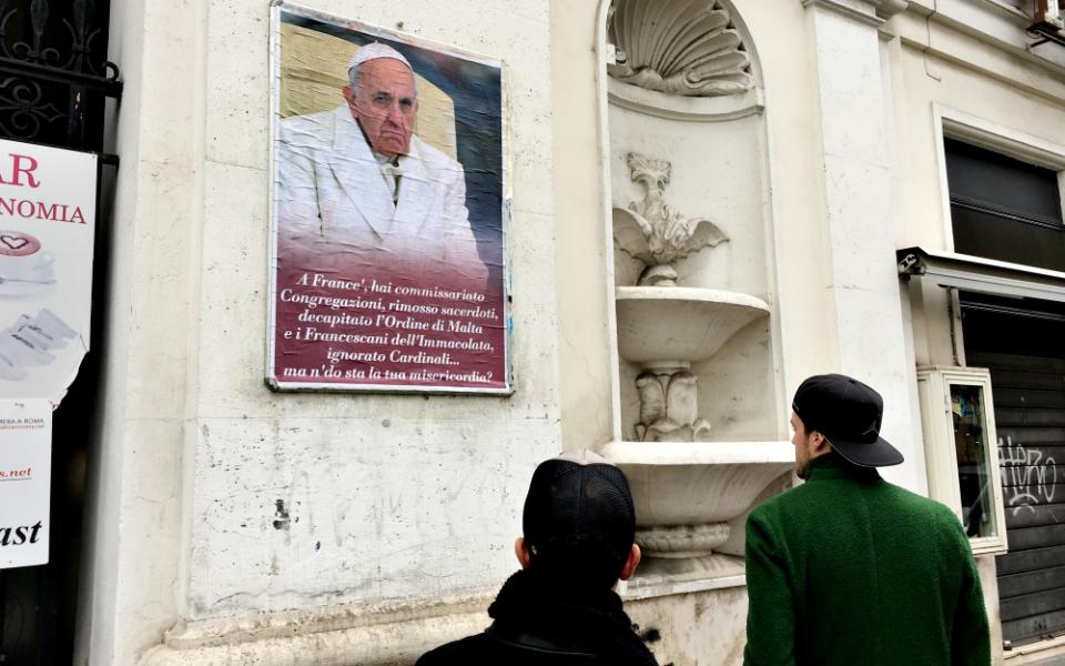 People look at a poster expressing criticism of Pope Francis in Rome Feb. 5, 2017. Numerous copies of the poster were placed in the center of Rome but were quickly covered or removed by city authorities. (CNS/Paul Haring)